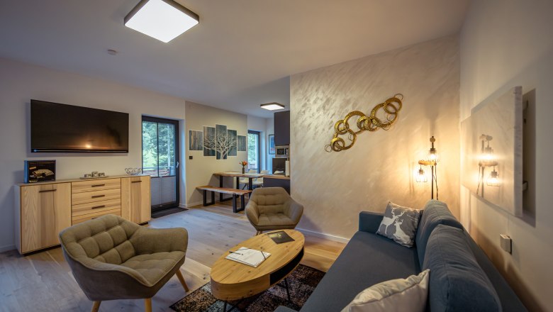 Ötscher Lodge, © Niederösterreich Werbung / Maximilian Pawlikowsky Moderná obývacia izba s pohovkou, kreslami, TV a jedálenským stolom.