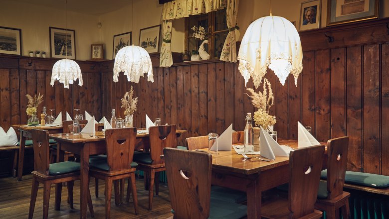 Rustikálny salón, © Niederösterreich Werbung/Andreas Hofer Útulný salónik s dreveným nábytkom, dekoráciami na stole a závesnými lampami.