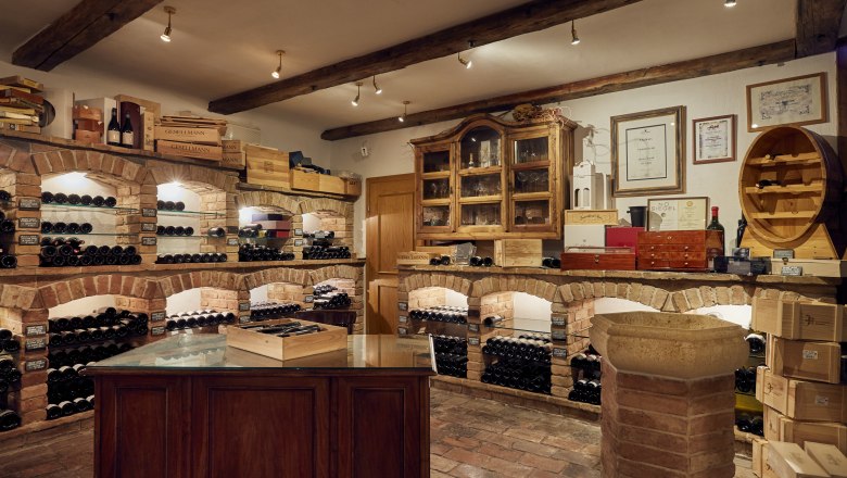 Špeciálne domáce víno, vinotéka, © Niederösterreich Werbung/Andreas Hofer Vínna pivnica s murovanými policami a fľašami vína.