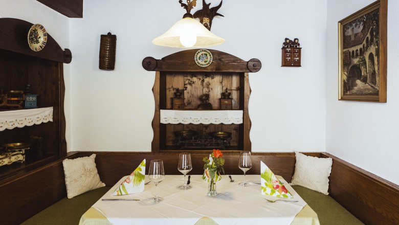 Izba pre hostí s láskyplnými detailmi, © Niederösterreich Werbung/David Schreiber Útulné posedenie v reštaurácii s dreveným nábytkom, dekoratívnymi detailmi a prestretým stolom.