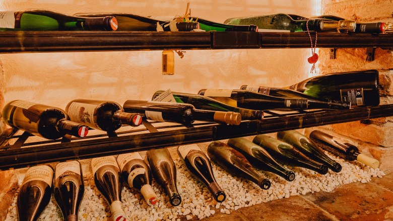 Široká ponuka vín, © Niederösterreich Werbung/Klaus Engelmayer Fľaše vína na poličke na bielych kameňoch.