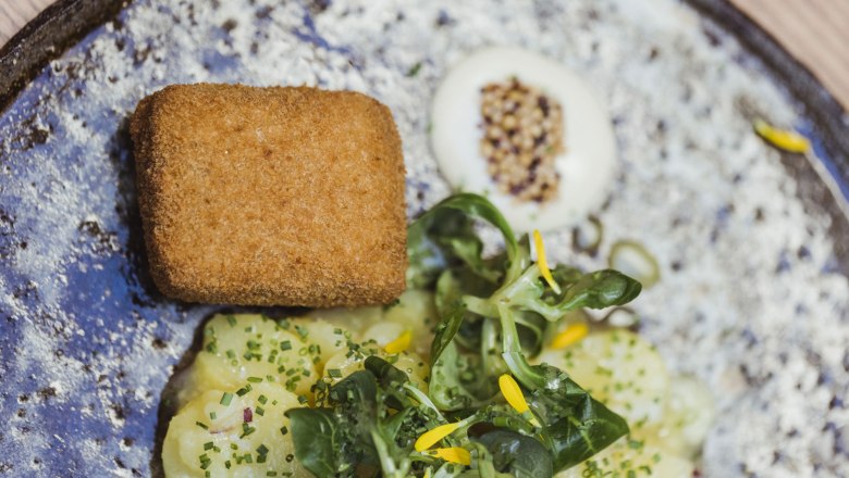 Teľacia hlava na vtáčej hlave a jablkový šalát, © Niederösterreich Werbung/David Schreiber Na tanieri opečená teľacia hlava, zemiakový šalát a jahňací šalát, ozdobený žltými kvetmi.