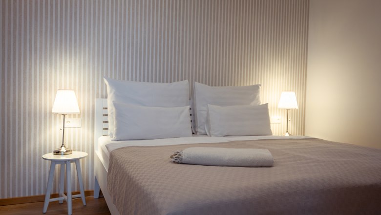 Apartmány Hausgnost, © Niederösterreich Werbung / Maximilian Pawlikowsky Moderná spálňa s manželskou posteľou, nočnými stolíkmi a lampami.