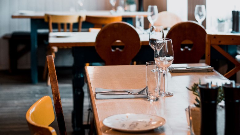 Mestská krčma s atmosférou, © Vinzenz Pauli/Philip Hinteregger Stôl v útulnej reštaurácii s dreveným nábytkom a pohármi na víno.