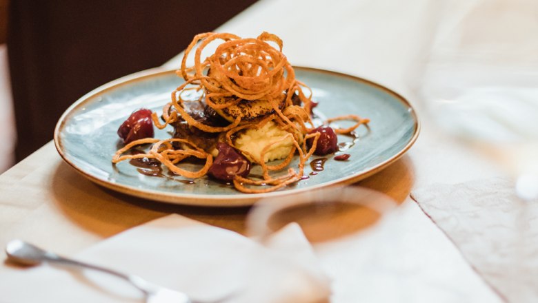 Glazovaná teľacia pečeň, © Niederösterreich Werbung/David Schreiber Mäsové jedlo s cibuľovými krúžkami na zemiakovej kaši a omáčke.