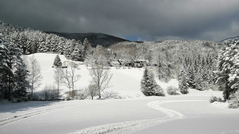 Vidiecke sídlo Oberhof v zime, © Landsitz Oberhof Zasnežená krajina s lesom a kopcami, tmavé mraky na oblohe.