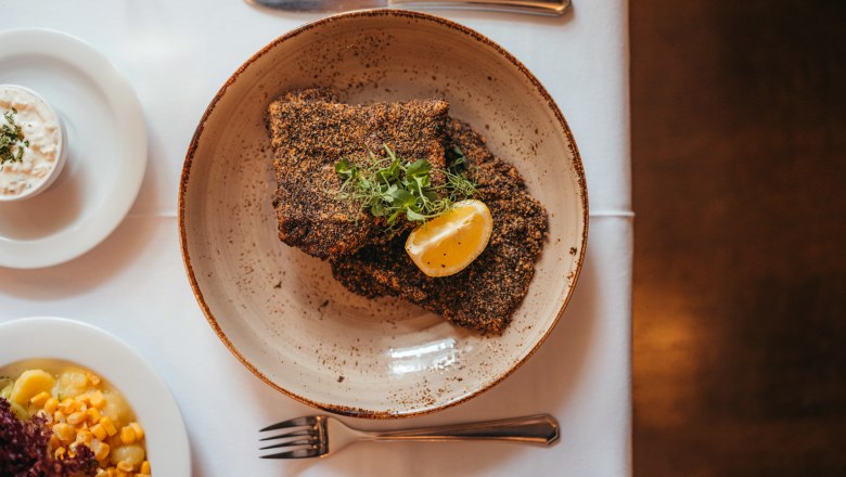 Filé z kapra Waldviertel z opátstva Zwettl obalené v sivom maku, © Niederösterreich Werbung/Daniela Führer Filé z kapra obalené v sivom maku s plátkom citróna a bylinkami na tanieri, s prílohami.