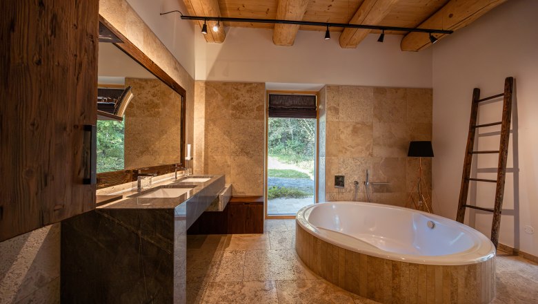 Rekreačný dom pri jazere, © Niederösterreich Werbung / Maximilian Pawlikowsky Moderná kúpeľňa s voľne stojacou vaňou, veľkým zrkadlom a dreveným trámovým stropom.