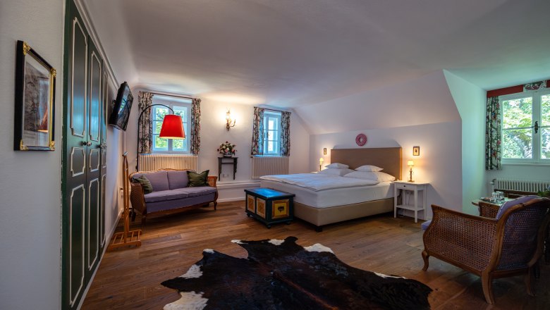 Vidiecke sídlo Oberhof, © Niederösterreich Werbung / Maximilian Pawlikowsky Útulná spálňa s manželskou posteľou, pohovkou, drevenou podlahou a kobercom z hovädzej kože.