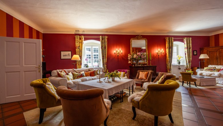 Lesnícka chata Langschlägerwald, © Niederösterreich Werbung / Maximilian Pawlikowsky Elegantná obývacia izba s červenými stenami, pohodlnými kreslami a veľkým zrkadlom.