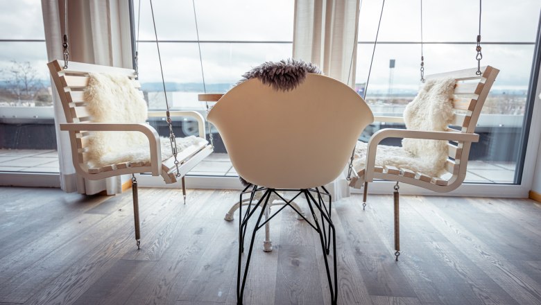 Alfred, © Niederösterreich Werbung / Maximilian Pawlikowsky Interiér s hojdacími kreslami a moderným kreslom pred veľkými oknami.