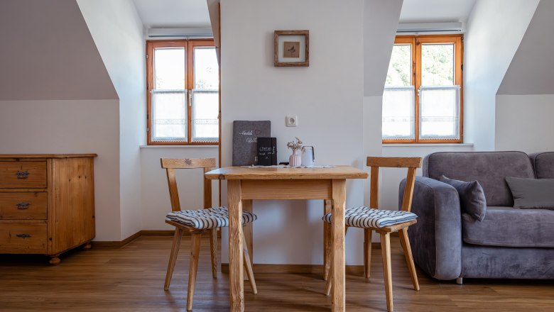 Leopold an der Ybbs, © © Niederösterreich Werbung/ Maximilian Pawlikowsky Útulný obývací priestor s dreveným stolom, dvoma stoličkami a pohovkou.