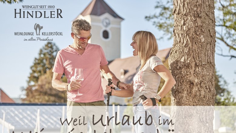 Vinárstvo Hindler, © Weingut Hindler Muž a žena stoja pred stromom s pohármi na víno a vychádzkovými palicami, v pozadí budova s vežou.