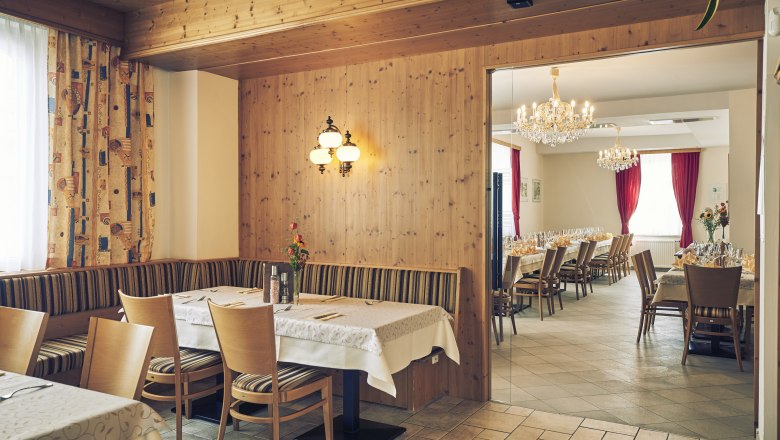 Hosťovská izba a banketová sála, © Niederösterreich Werbung/Andreas Hofer Útulná hosťovská izba s drevenými stenami a priľahlou banketovou sálou s lustrami a prestretými stolmi.