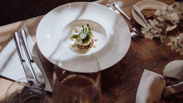 Údený tatarák zo pstruha na zemiakových plackách, © Niederösterreich Werbung/thecreatingclick.com Na drevenom stole s príborom a pohárom vína tanier s tatarákom z údeného pstruha na zemiakovej placke, ozdobený bylinkami a kvetmi.