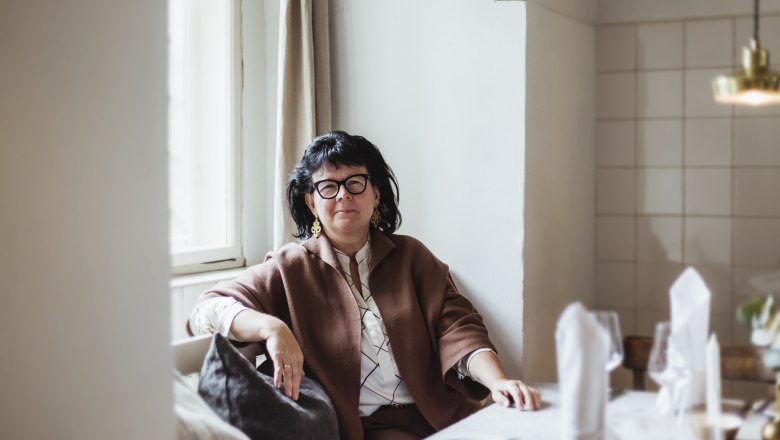 Domáca pani Sandra Blauensteiner, © Niederösterreich Werbung/David Schreiber Žena sediaca pri prestretom stole v útulnej miestnosti.