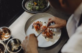 Kuchyňa: odvážna, divoká, zakorenená v regióne, © Niederösterreich Werbung/Sophie Menegaldo Šéfkuchár pripravuje jedlo na tanieri.