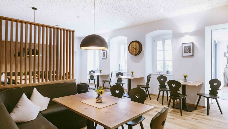 Útulná atmosféra v jedálni zaliatej svetlom, © Astrid Bartl Moderný salón s dreveným nábytkom a štýlovým osvetlením.