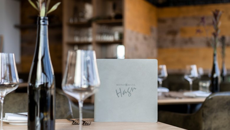 Pohár na víno, © Stefanie Winter Položený stôl v reštaurácii s pohármi na víno, fľašou vína a jedálnym lístkom.