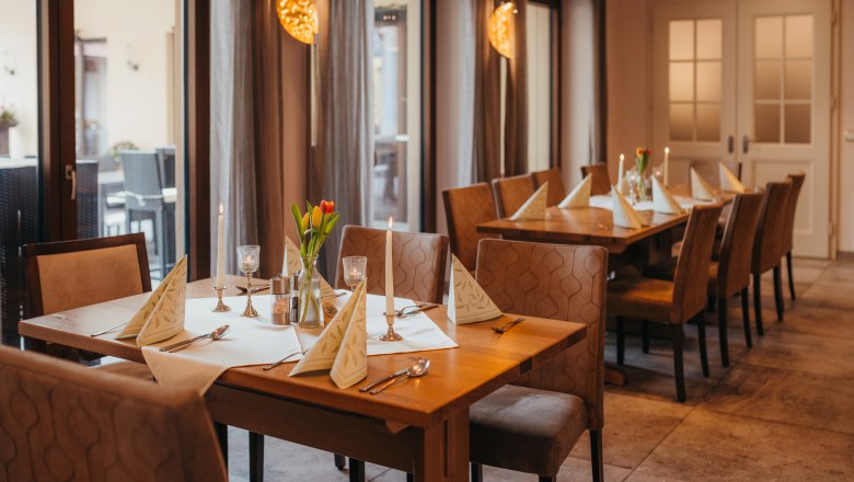 Pub s kabaretnými večermi a ranným pivom, © Niederösterreich Werbung/Daniela Führer Útulný stôl v krčme so sviečkami a kvetmi.