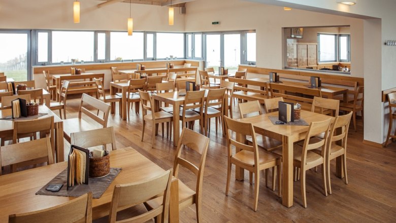 Pohľad do interi&eacute;ru elegantnej Viechy s dreven&yacute;m n&aacute;bytkom a veľk&yacute;mi oknami.