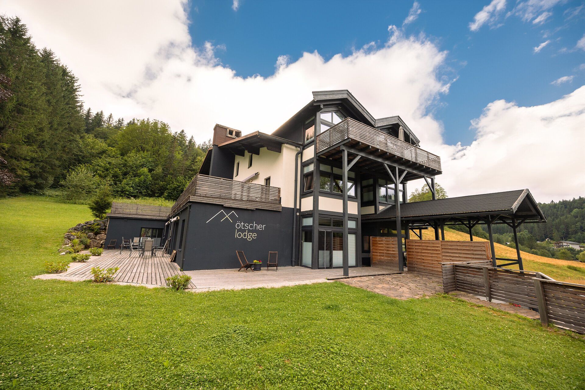 Ötscher Lodge v zelenom zalesnenom prostredí s modrou oblohou.