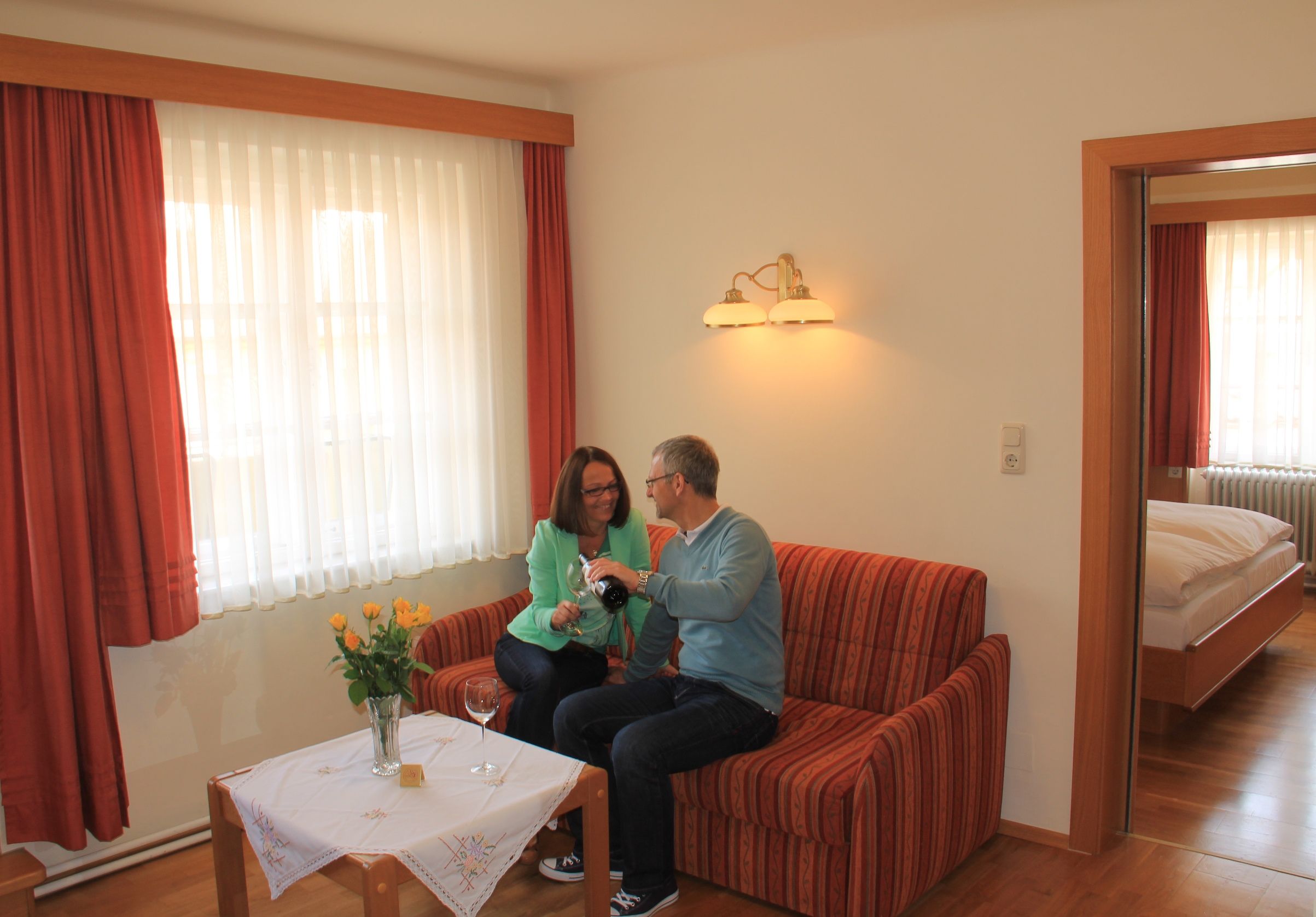 Pár sedí na pohovke v útulnom byte a nalieva si víno.