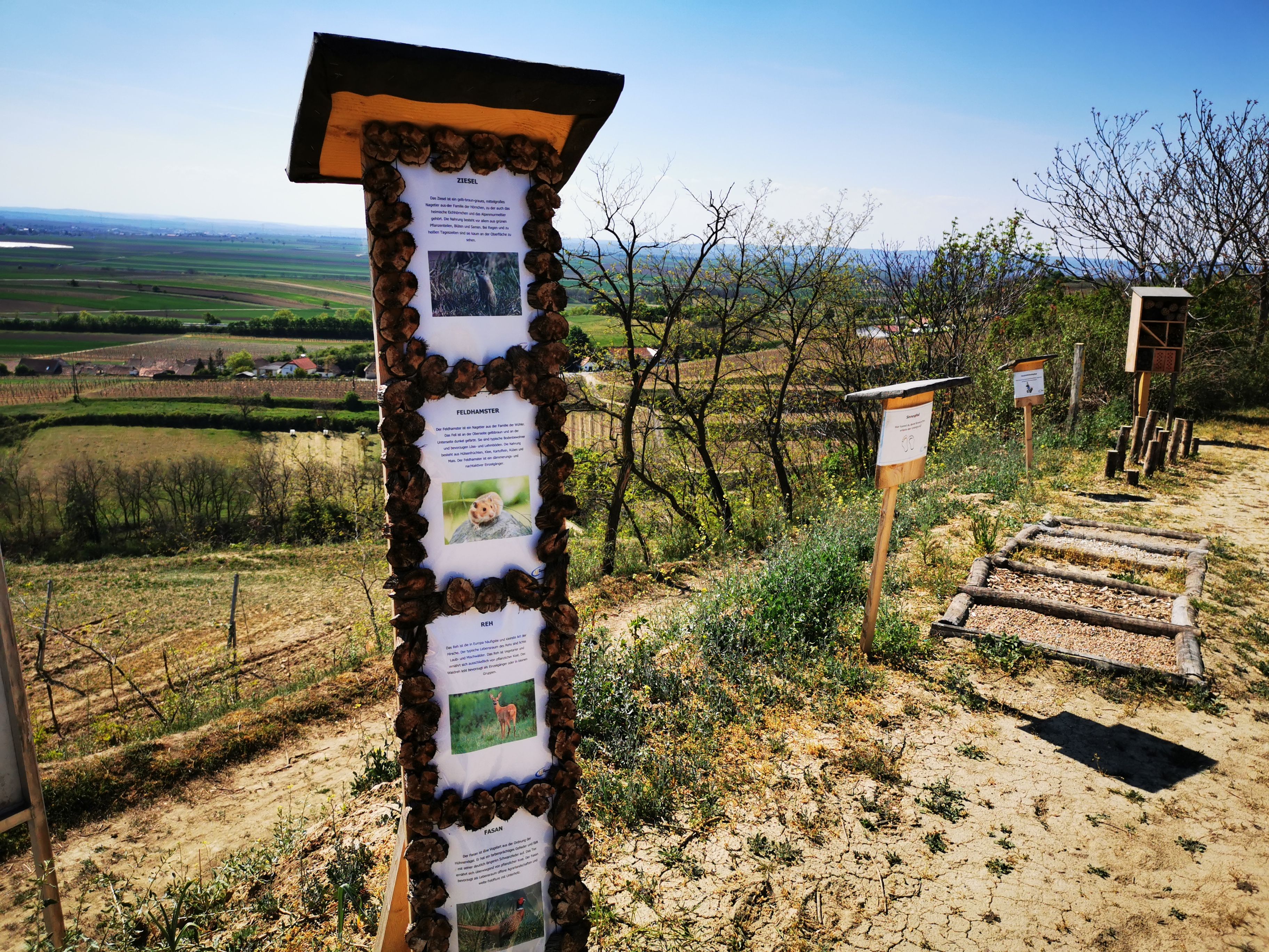 Náučný chodník s informačnými tabuľami vo vidieckej krajine.