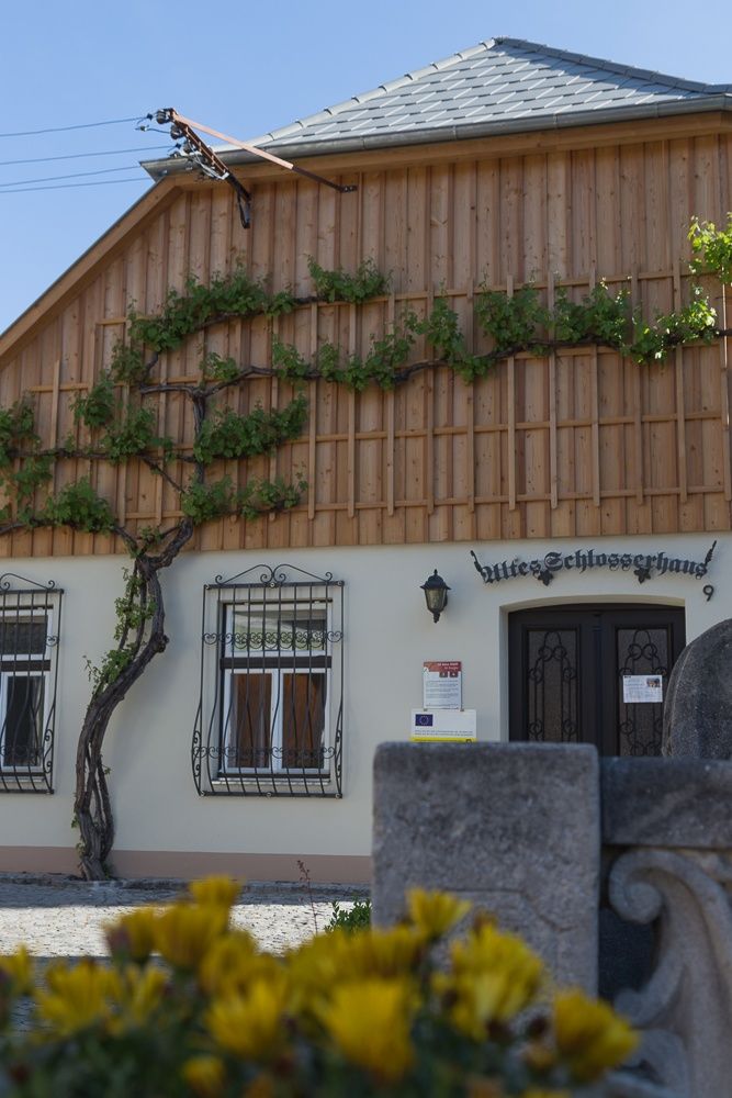 Fasáda starého zámočníckeho domu s dreveným obložením a popínavými rastlinami.