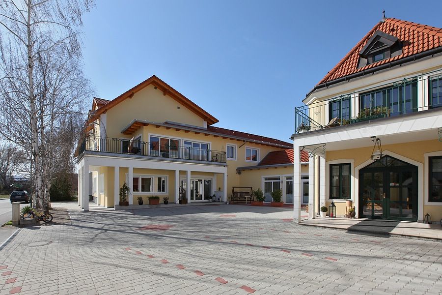 Pohľad zvonku na žltý vinohrad s červenými strechami a vydláždeným dvorom.