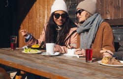 Dvaja ľudia na bežkách na zasneženej trase v zimnej horskej krajine.