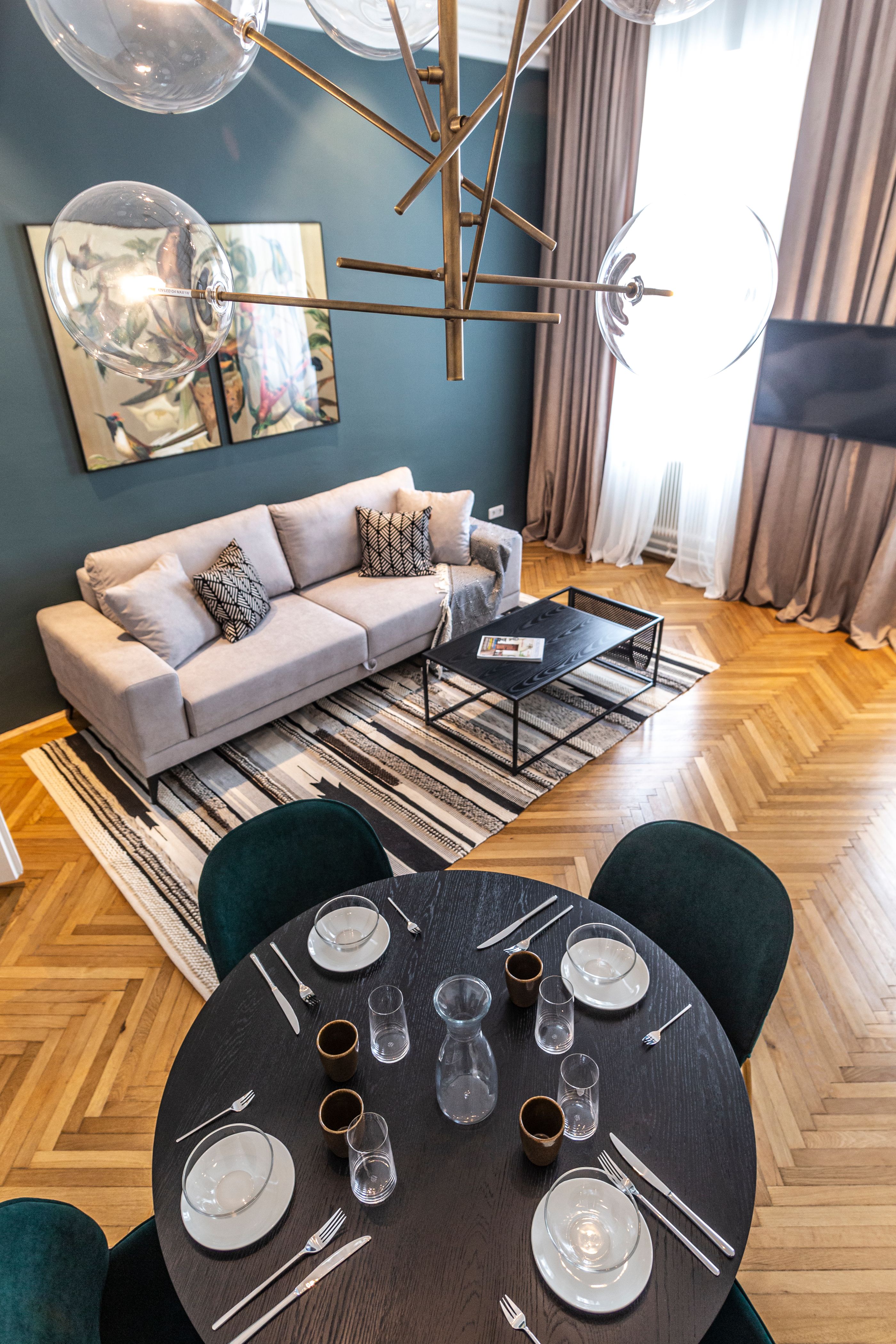 Moderná obývacia izba s pohovkou, konferenčným stolíkom, kobercom a jedálenským stolom s prestieraním.