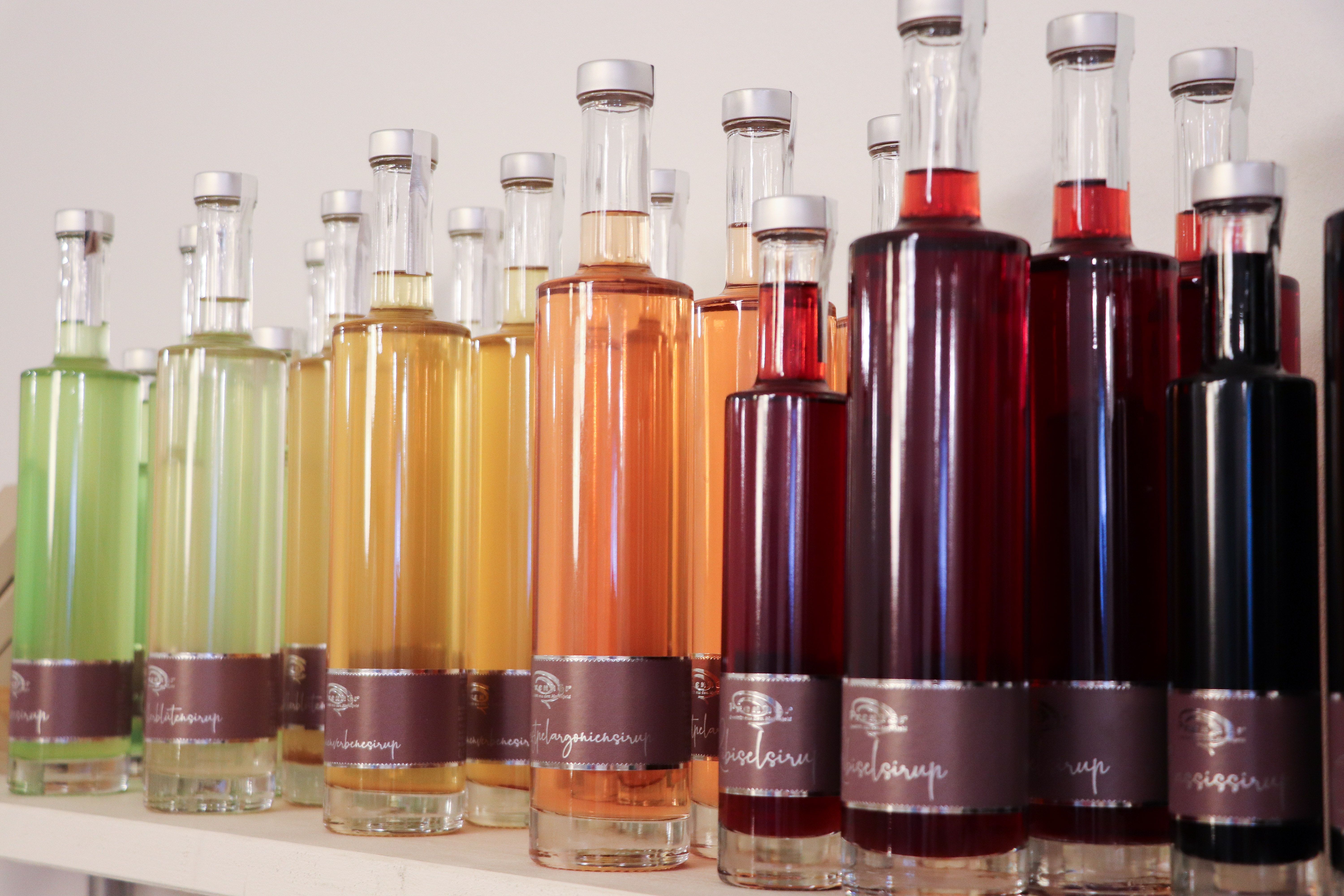 Rôzne farebné fľaše so sirupom v rade na polici.