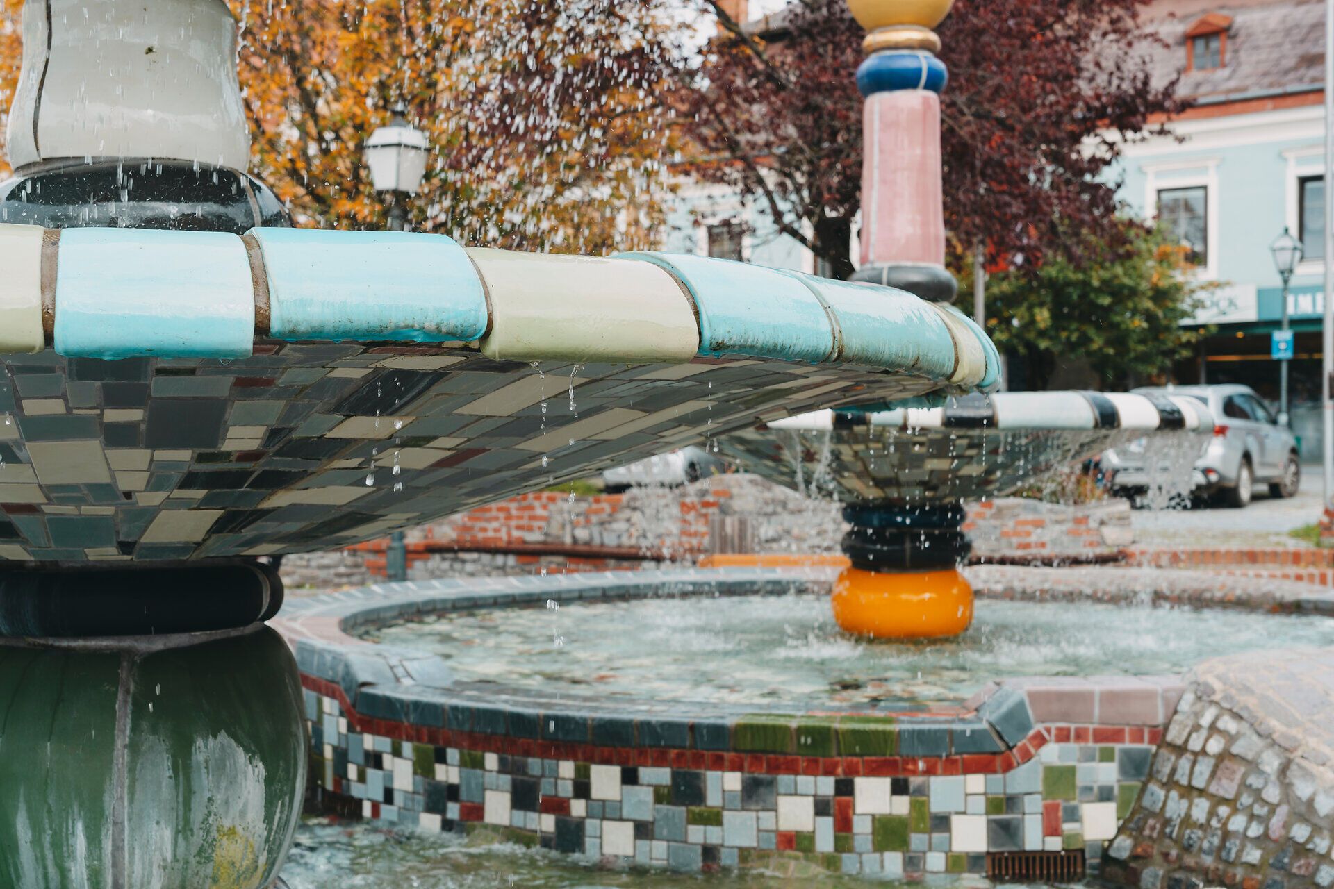 Jeseň dodáva fontáne Hundertwasser zvláštne čaro, keď sa voda jemne vlní na farebných dlaždiciach. Toto miesto obklopené pestrofarebnými stromami a príjemnou atmosférou vás pozýva, aby ste sa tu zdržali a zasnívali.
