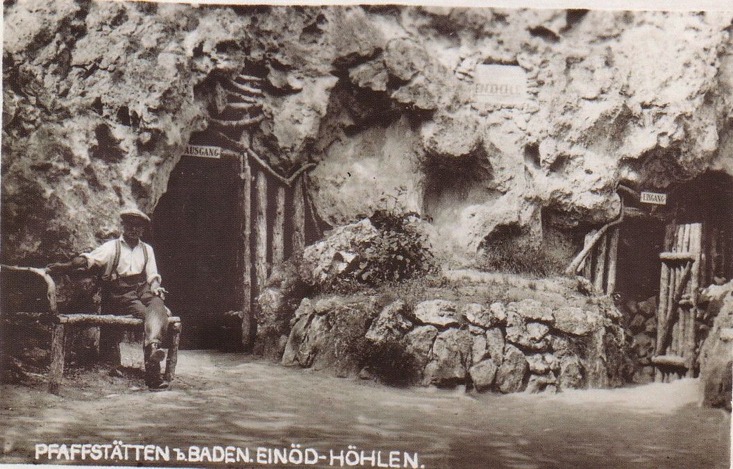 Historická fotografia jaskyne Einödhöhle v Pfaffstätten v Bádensku s mužom na lavičke pred vchodom do jaskyne.