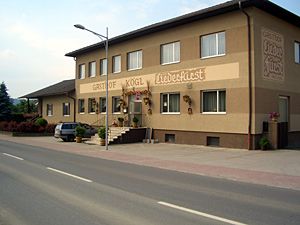 Dvojpodlažná budova s nápisom "Gasthof Kögl".