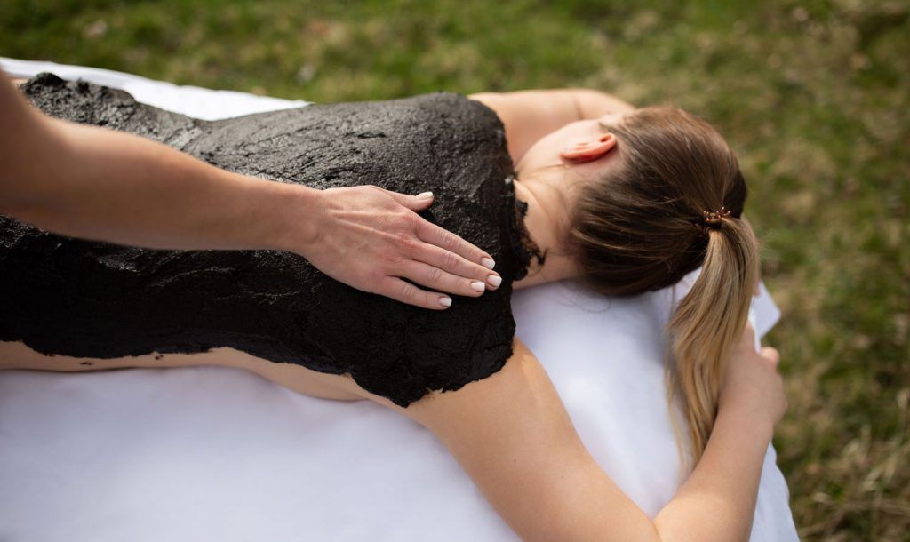 osoba dostane na chrbát bahenný balíček na čerstvom vzduchu.