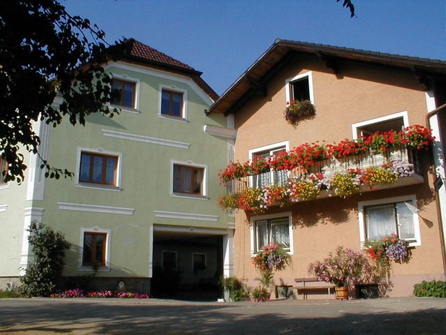 Dve hospodárske budovy s farebnými kvetmi na balkónoch.