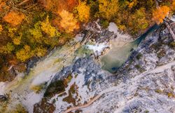 Die bunten Blätter der Bäume spiegeln die goldene Herbstsonne wider und schaffen eine malerische Kulisse für den klaren, plätschernden Bach, der durch die Schlucht fließt. Wanderer können die frische, klare Luft genießen und die beeindruckenden Felsformationen bewundern, die diesen Naturpark zu einem wahren Paradies der Blicke machen.