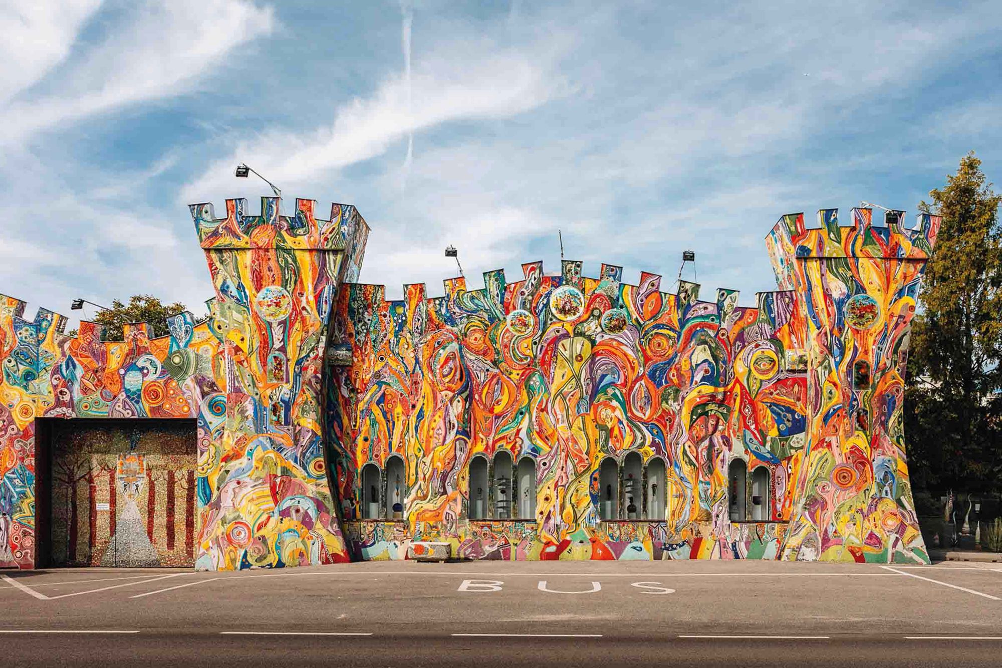 Farebne maľovaná fasáda budovy v tvare hradu s vežami.