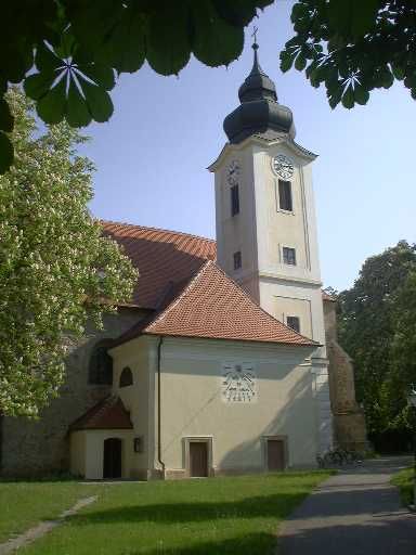 Farský kostol v Zwentendorfe s vežou a hodinami, obklopený stromami.