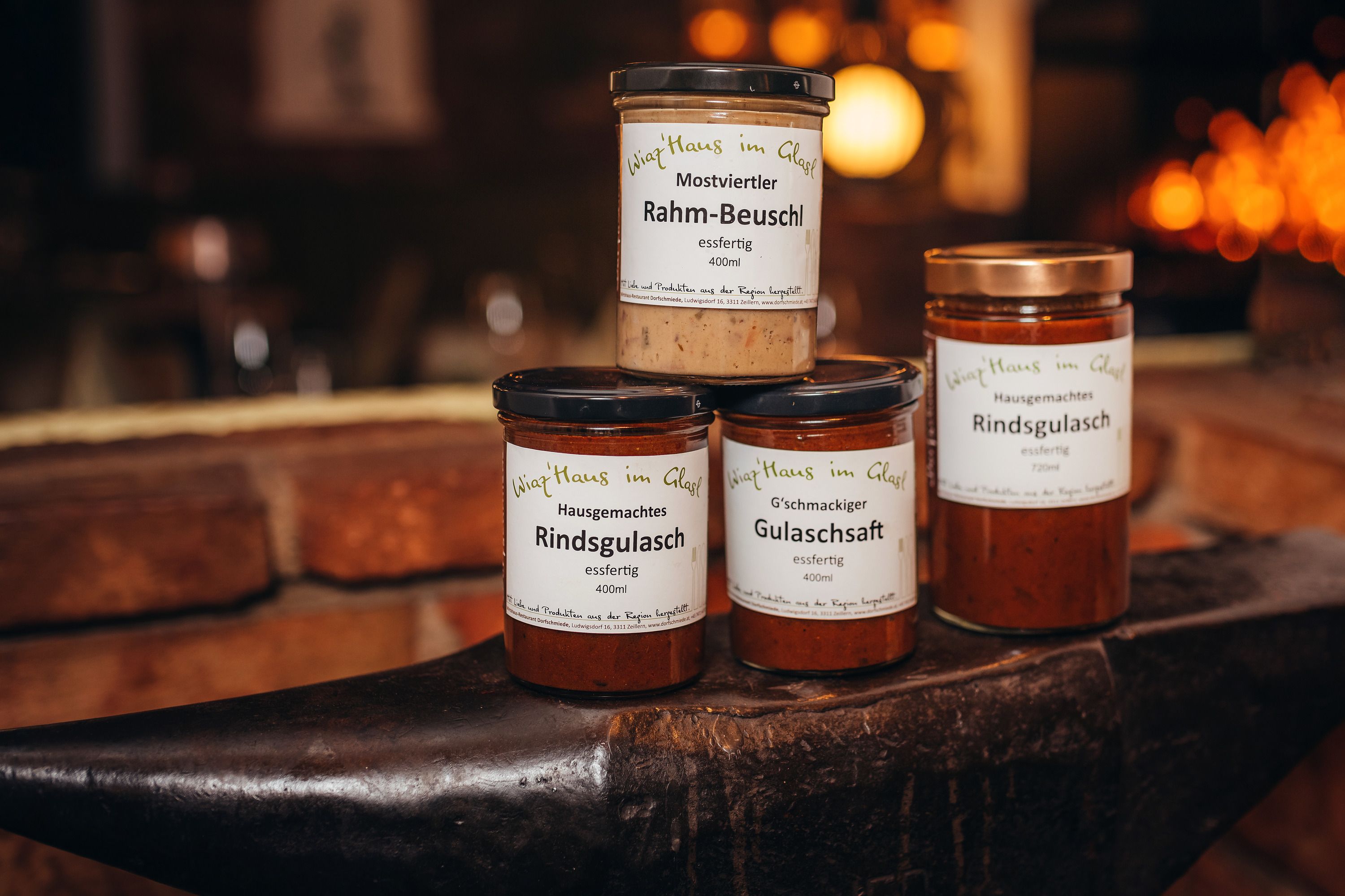 Tri nádoby s hotovými jedlami na kovadline s nápisom "Wirtshaus im Glas".