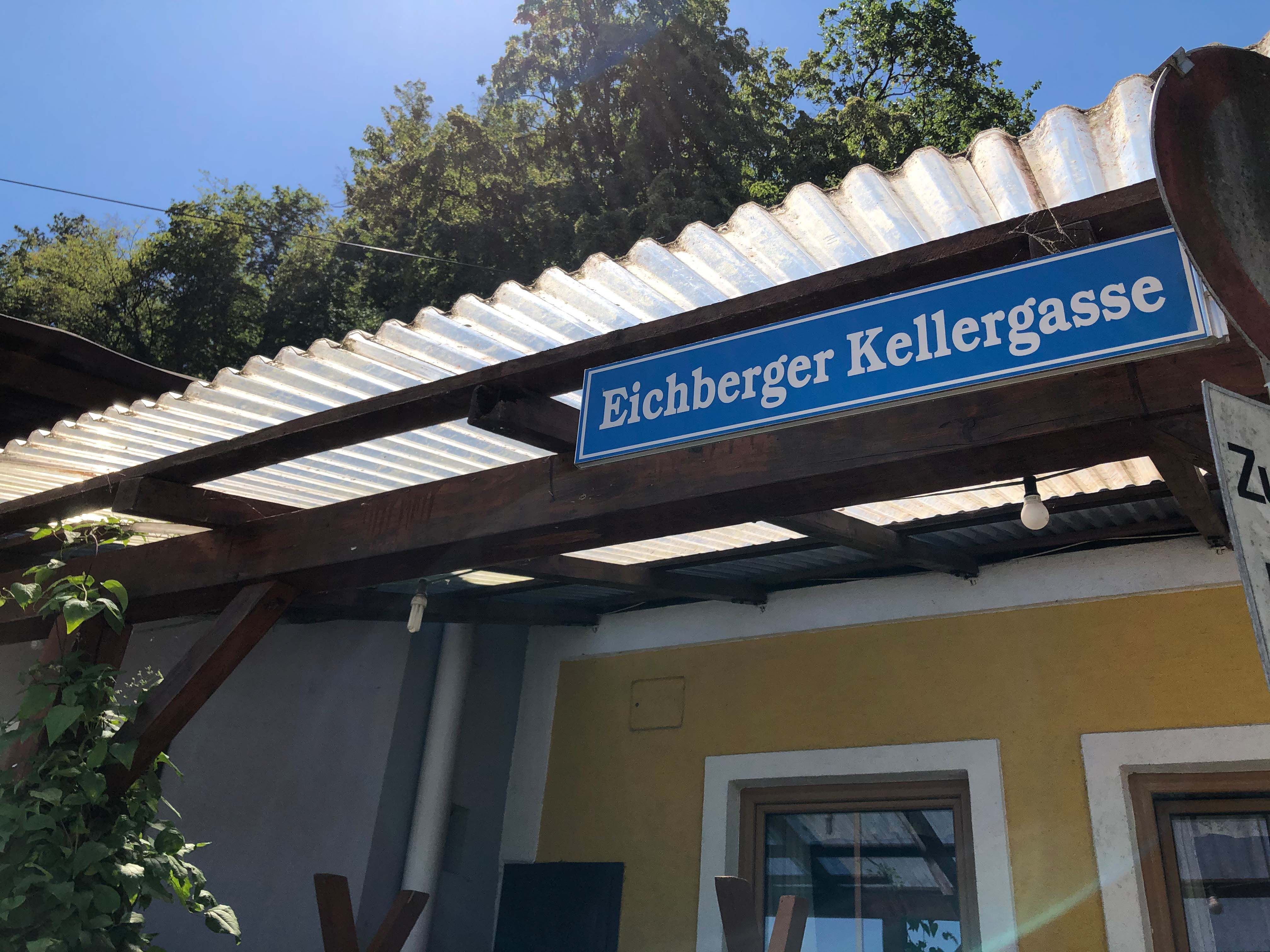 Nápis "Eichberger Vínne uličky" na budove so strechou z vlnitého plechu.