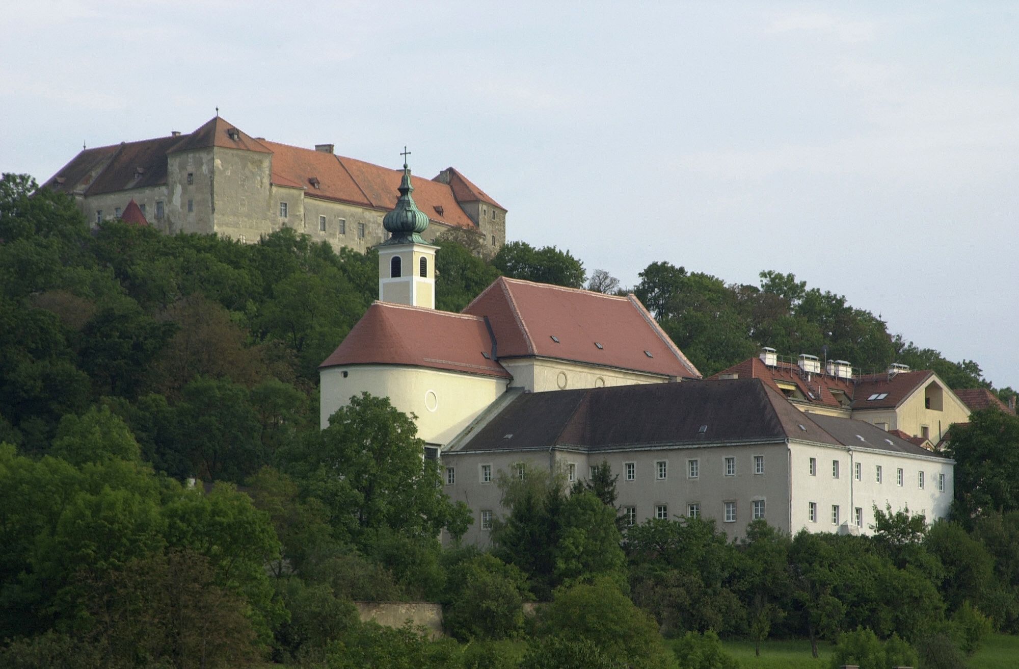 Hrad Neulengbach na kopci s okolitými budovami a stromami.