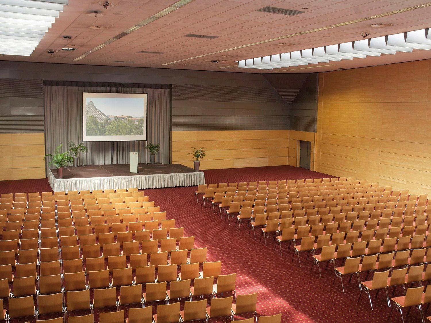 Veľká konferenčná sála s pódiom a radmi stoličiek.