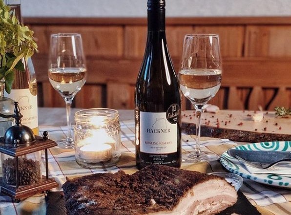 St&ocirc;l s fľa&scaron;ou v&iacute;na, dvoma poh&aacute;rmi, sviečkou a miskou na m&auml;so.