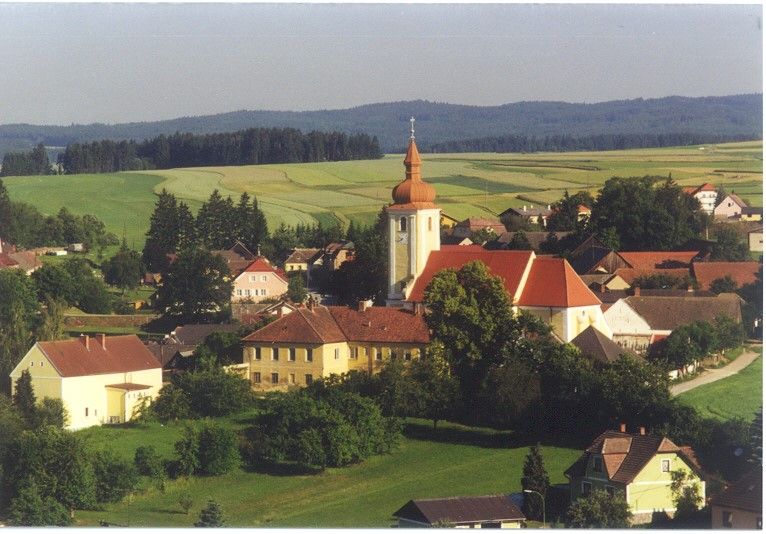 Letecký pohľad na Waldkirchen an der Thaya s kostolom a okolitými domami, obklopený poľami a lesmi.