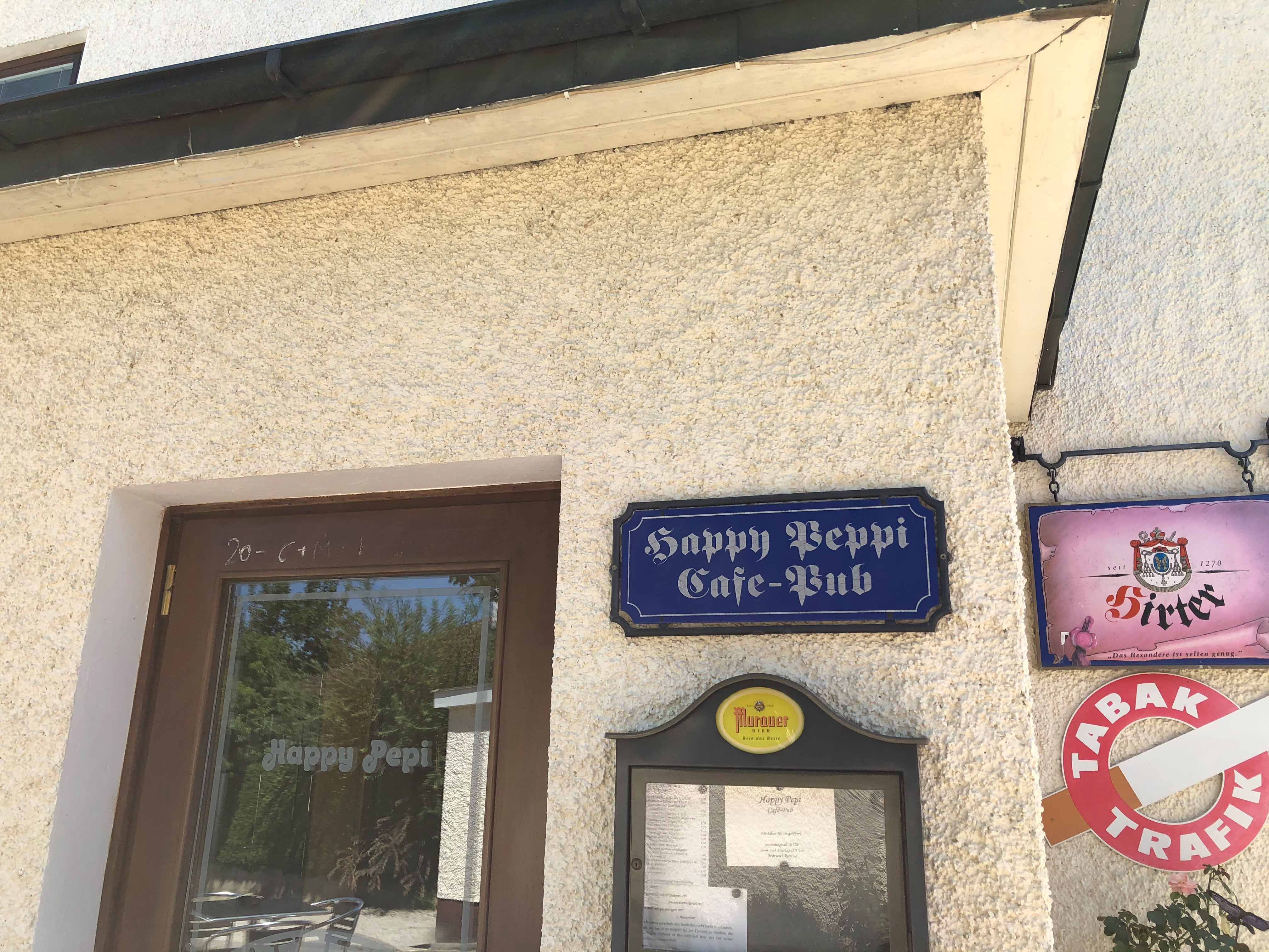 Vchod do kaviarne Happy Pepi s nápismi a jedálnym lístkom na stene.