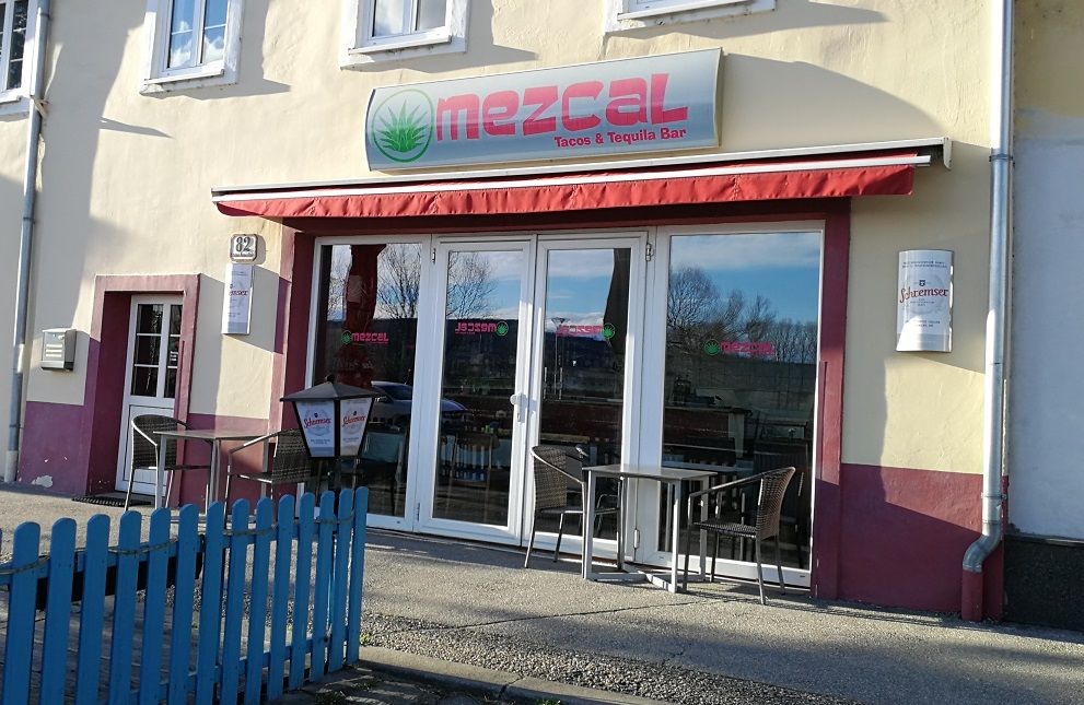 Exteriérový pohľad na reštauráciu Mezcal s červenými markízami a sedením.