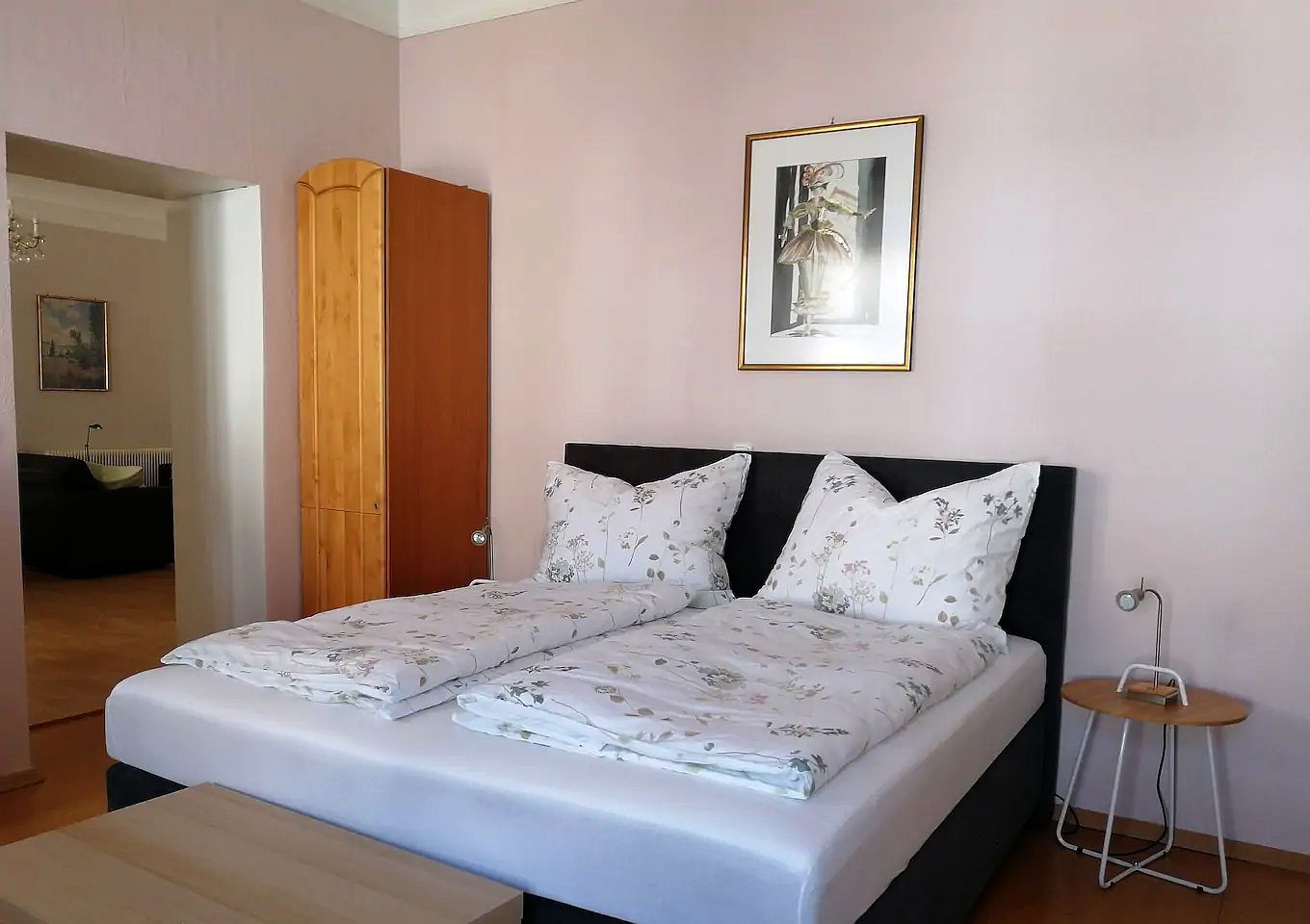 Spálňa s manželskou posteľou, drevenou skriňou a nástennou maľbou.